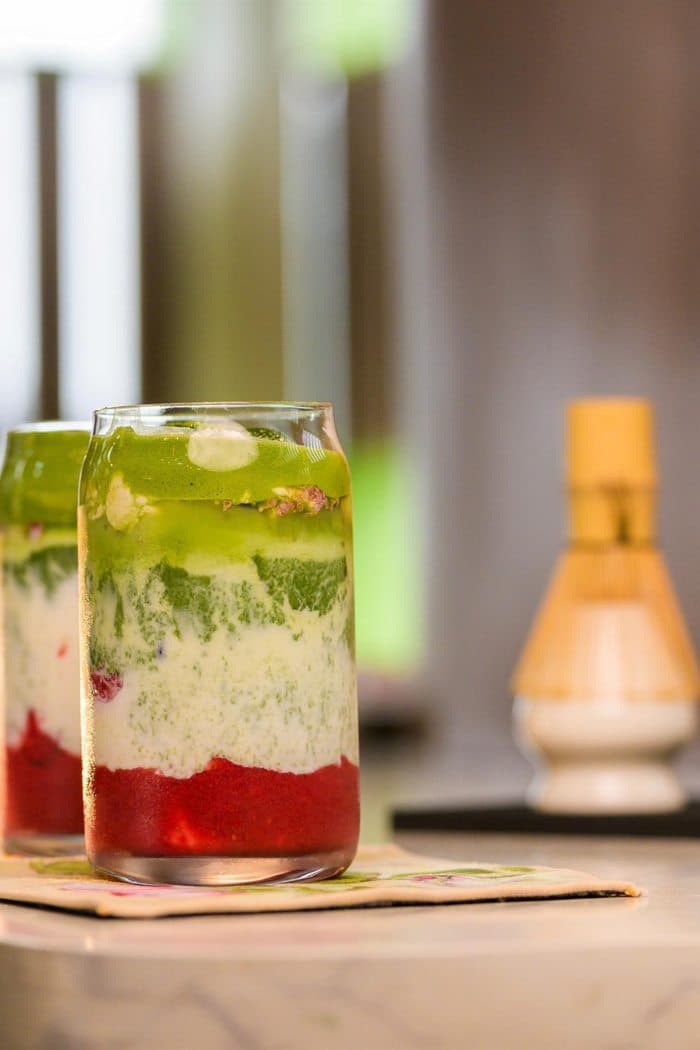 Strawberry matcha lattes beside a bamboo whisk at the matcha bar