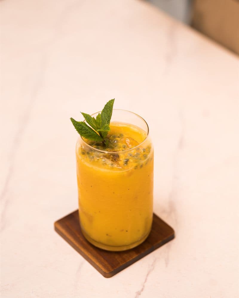 Passion fruit and mango cooler with fresh mint on a marble counter