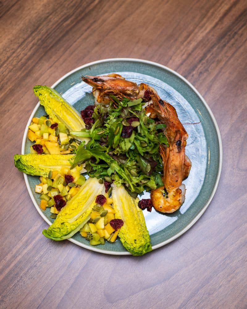 Grilled prawns over mixed greens with baby gem lettuce and mango salsa