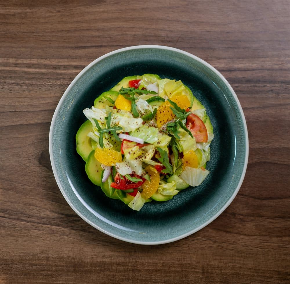 Fattouch Pioppi — avocado, orange, cucumber and radish salad on a green ceramic plate